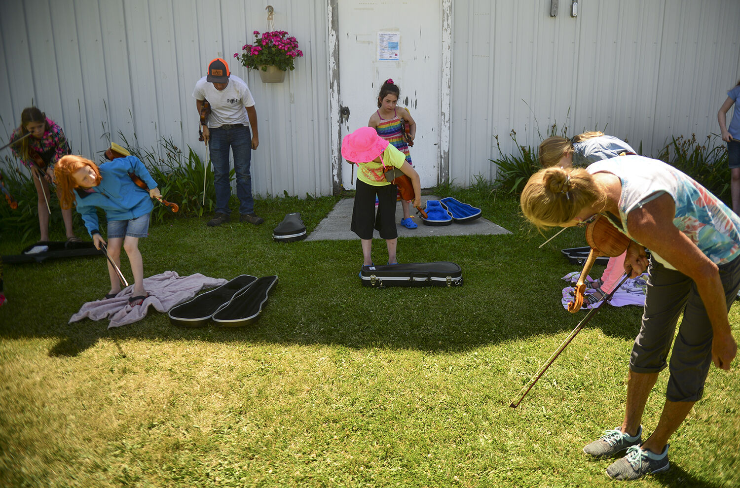 The group of fiddle players practices taking a synchronized bow